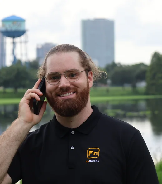 Nick Tidrick, founder of FnButton, outside in St. Petersburg with the downtown skyline behind him, wearing an FnButton polo